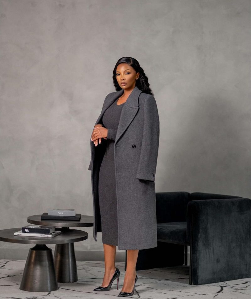 A trench coat layered over a fitted dress for a polished transitional outfit.