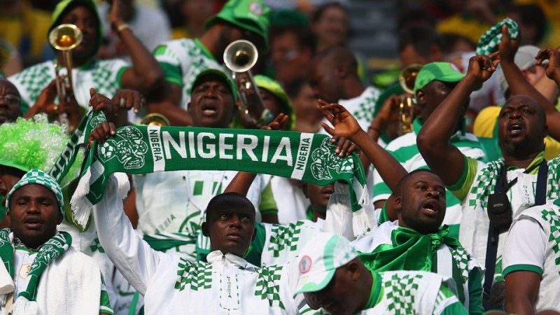 Nigerian football fans wearing matching outfits during a match.