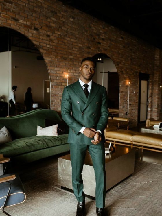 A close-up of a sophisticated, jewel-toned emerald green suit worn by a groom at a luxury wedding.