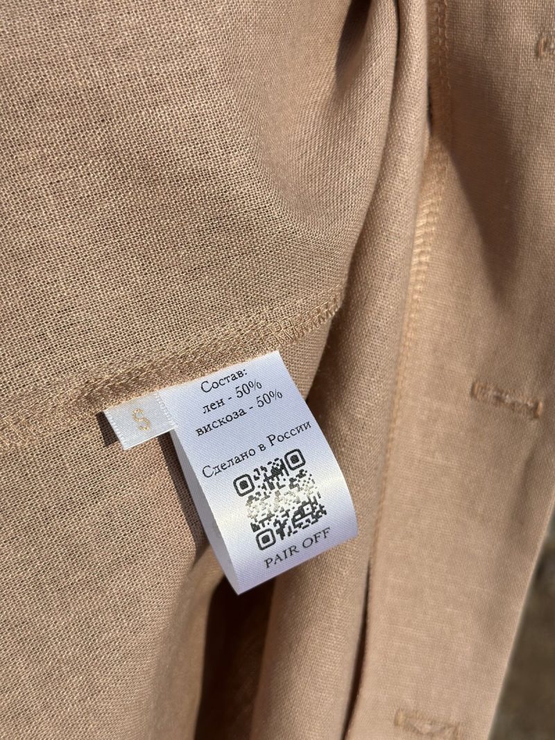 Close-up of a digital tag on a luxury garment, illustrating the use of blockchain for authenticating Artisanal Sovereignty and ensuring the Value Proposition for global investors.