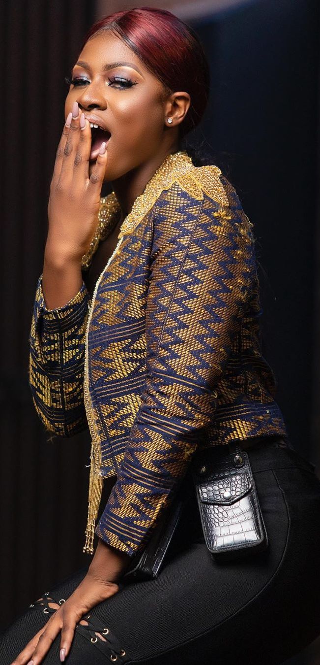 Close-up of a high-fashion tailored jacket featuring an intricate Kente weaving pattern, demonstrating the high market valuation of lost textiles when revived by Diaspora designers.