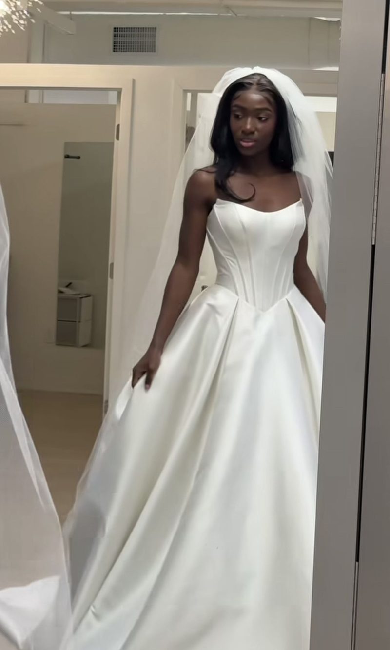 A structured, high-end white wedding dress for 2025 with a sharp cat-ear neckline and a minimalist silk finish.