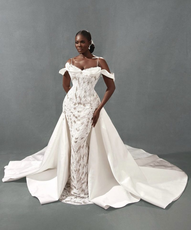 A versatile 2026 wedding fashion trend featuring a sleek column gown with a detachable cathedral-length overskirt for a dramatic ceremony entrance.
