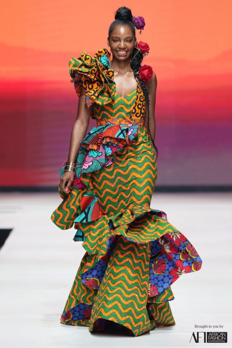 A runway model wearing a contemporary, vibrant African-inspired dress, showcasing global design influence.