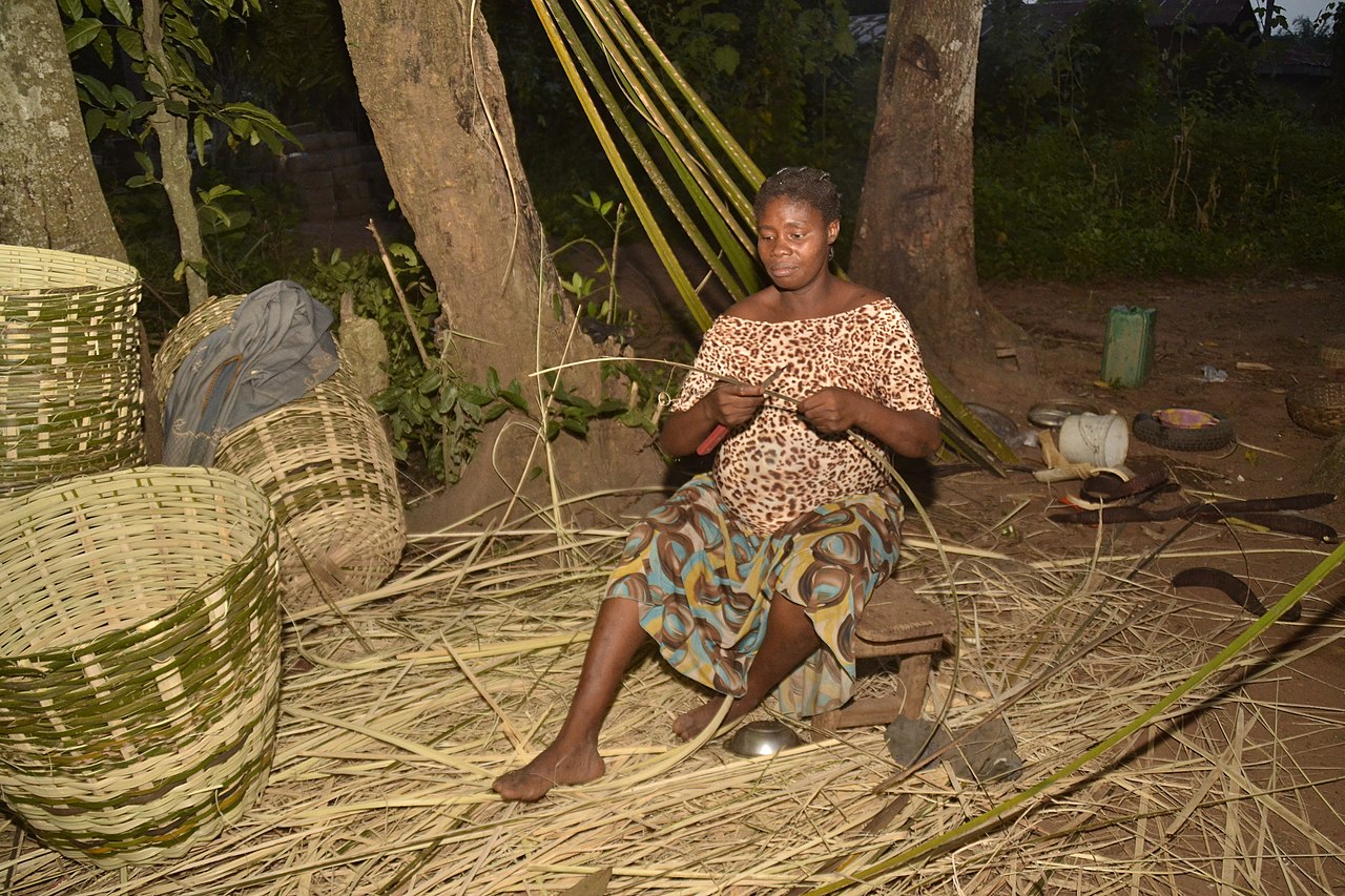 A picture of a woman weaving a basket, evoking memories of Nigerian culture.