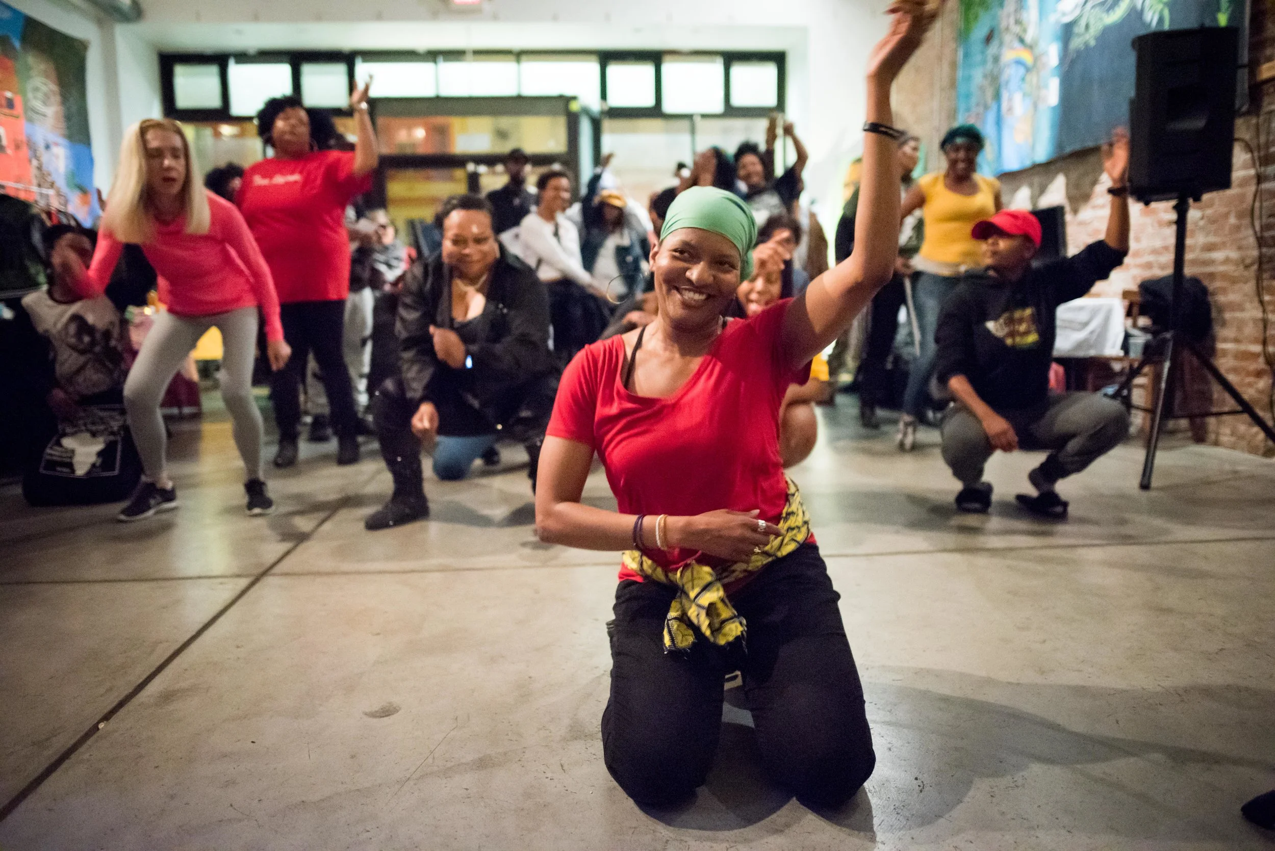 Woman leading Ndombolo dance class with a diverse group of participants
