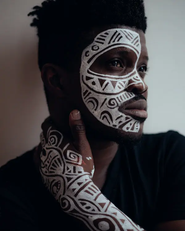 An image showing a guy with body painting on his face and hands
