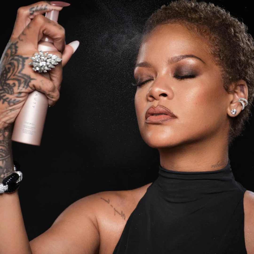An image showing Rihanna applying a setting spray to lock her makeup in
