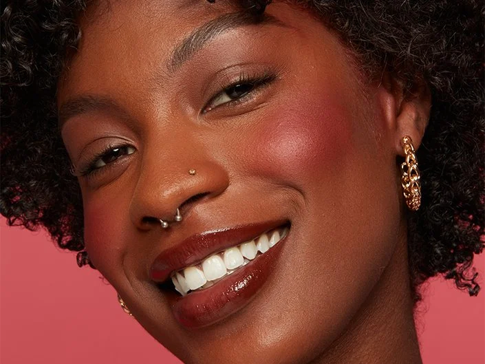 An image showing a lady wearing deep pink blush for deep skin