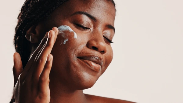 An image showing a lady prepping her skin by rubbing a moisturiser. One step on how to make makeup last in African heat and humidity
