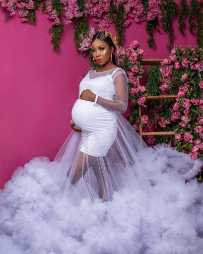 A pregnant woman wearing a structured gown with a flare exterior for a pregnancy photoshoot