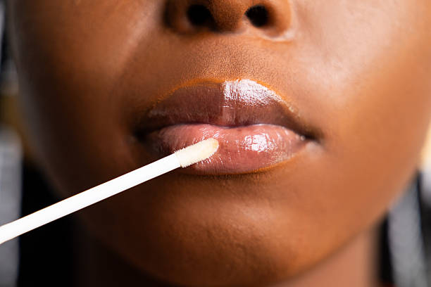  An image showing a lady applying clear lip gloss
