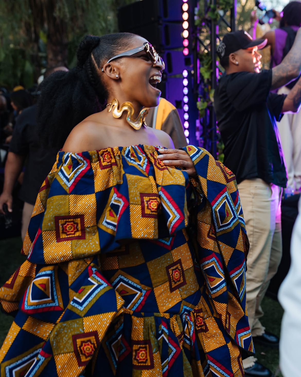 An image showing Julie Adenuga dressed in a dress made with African prints and glasses, an example of second-generation African diaspora fashion