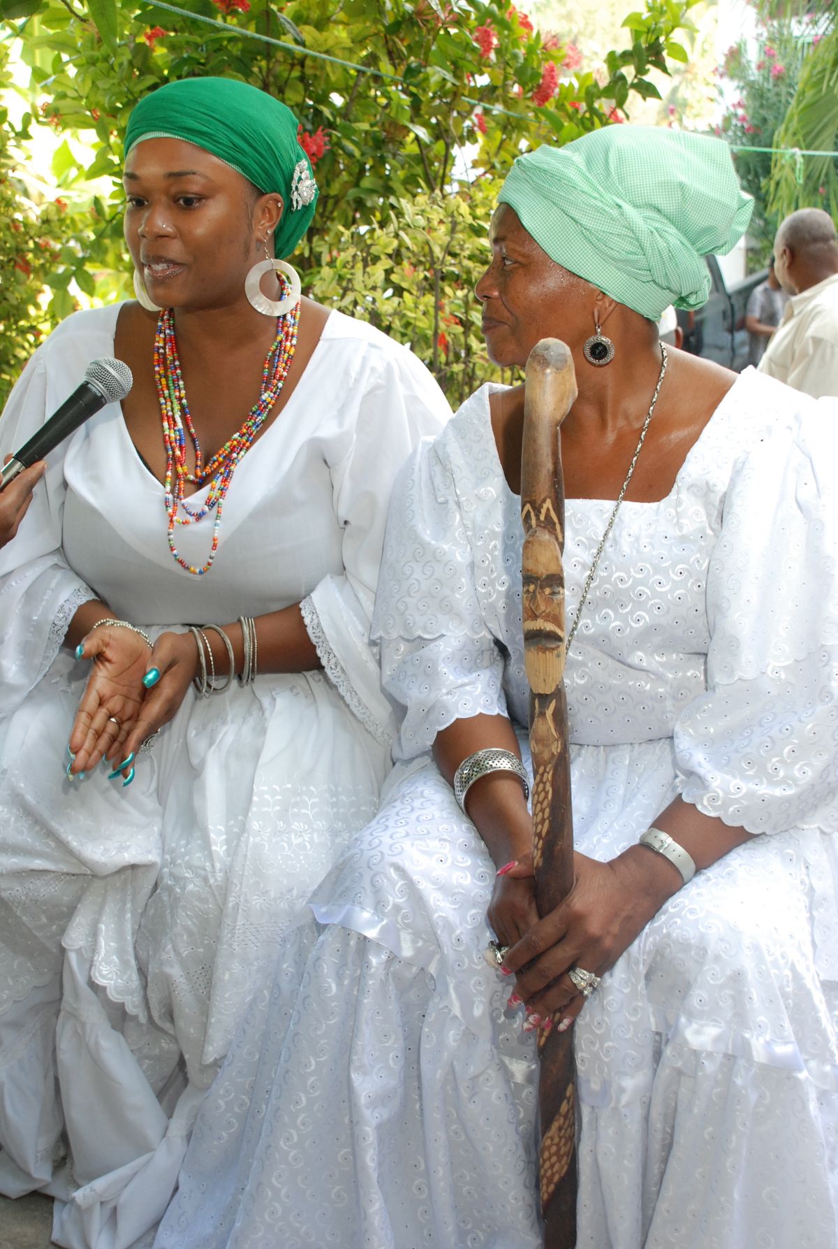Image description: Haitian Vodou initiate wearing white robe and colored headwrap showing lwa-specific symbolism.