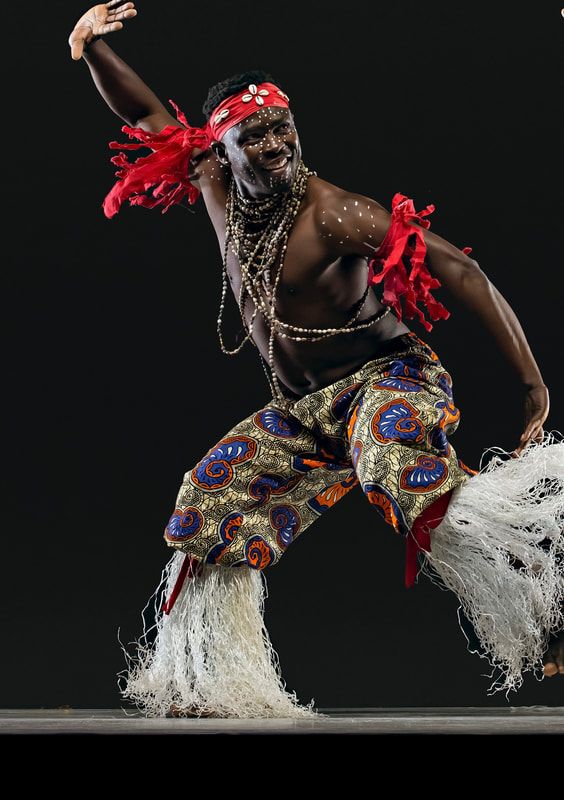 Intore dancer in mid-leap during Burundi warrior dance, showcasing traditional spear and costume.