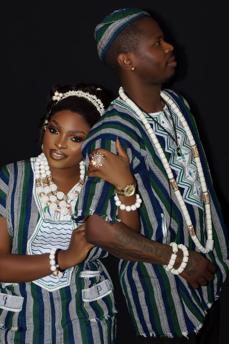 An image showing a couple wearing blue and green striped mende country cloth outfits with white patterned detailing.