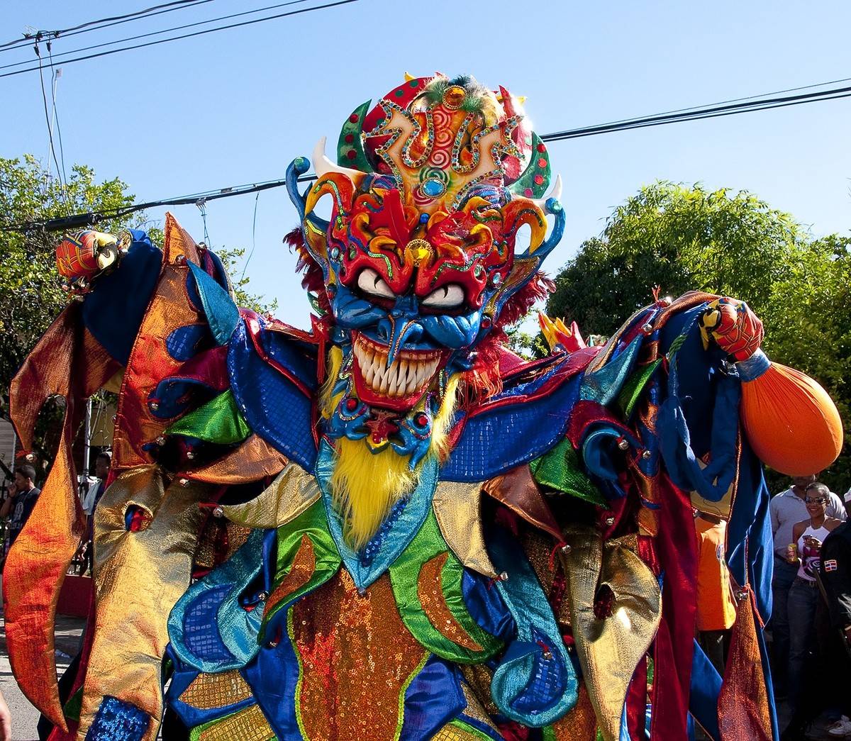 Woman performing as Diabla Cojuela in La Vega Carnival with traditional mask, costume, and vejiga whip
